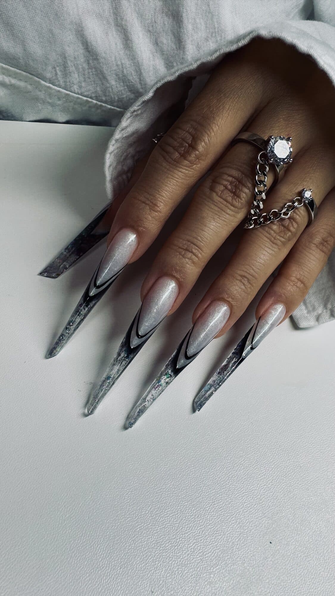 Grey marble stiletto nails with a black swirl design