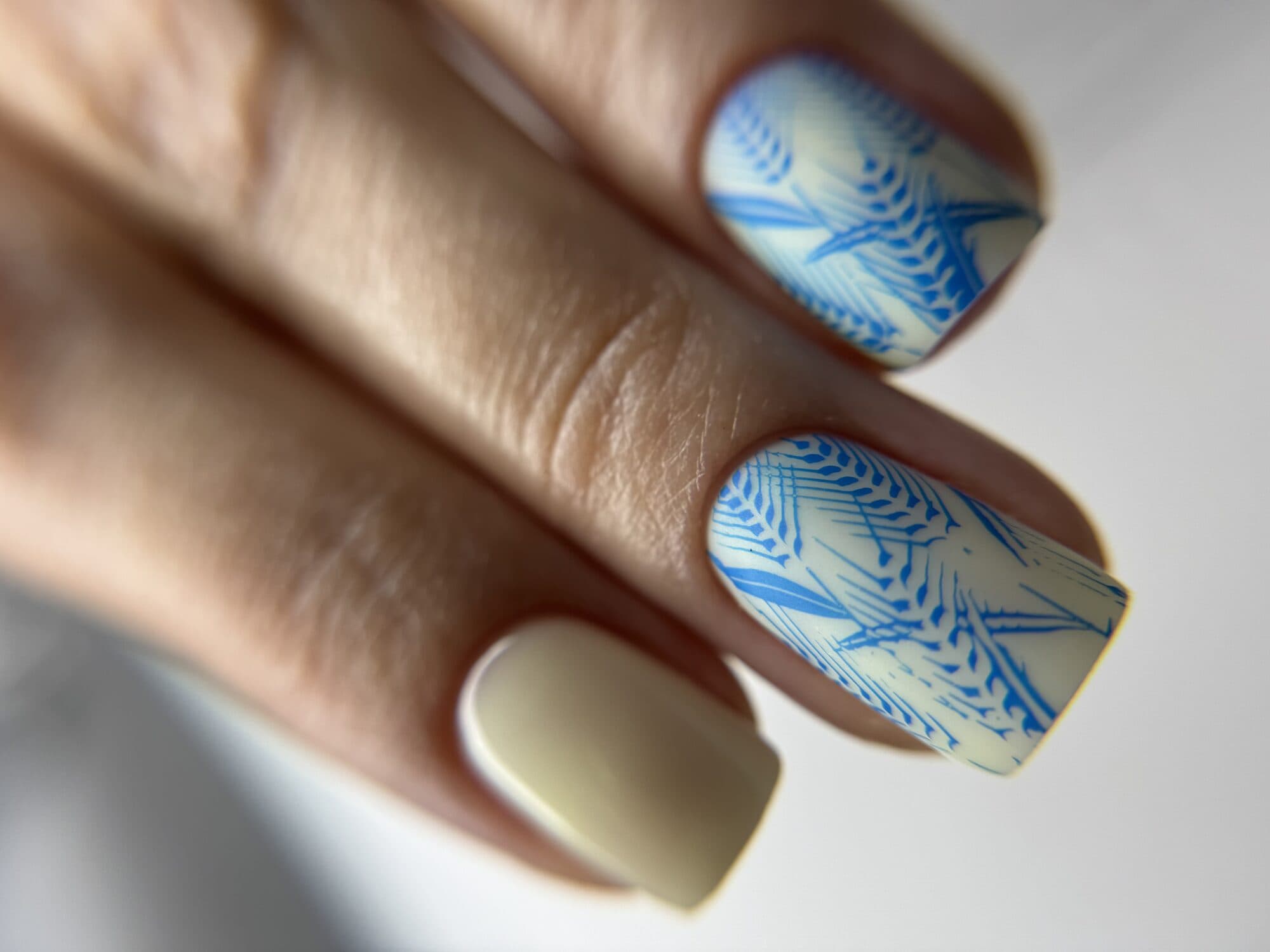 Pastel yellow and blue nails with hand-painted winter leaf art
