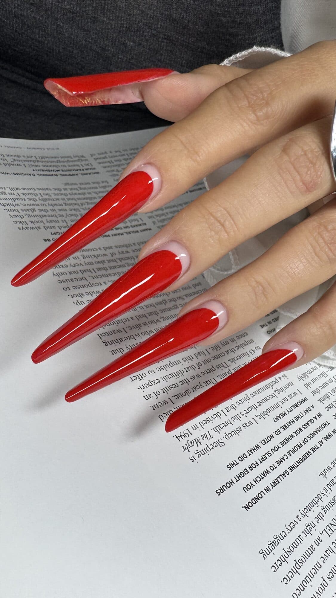 Long red coffin nails resting on an open book