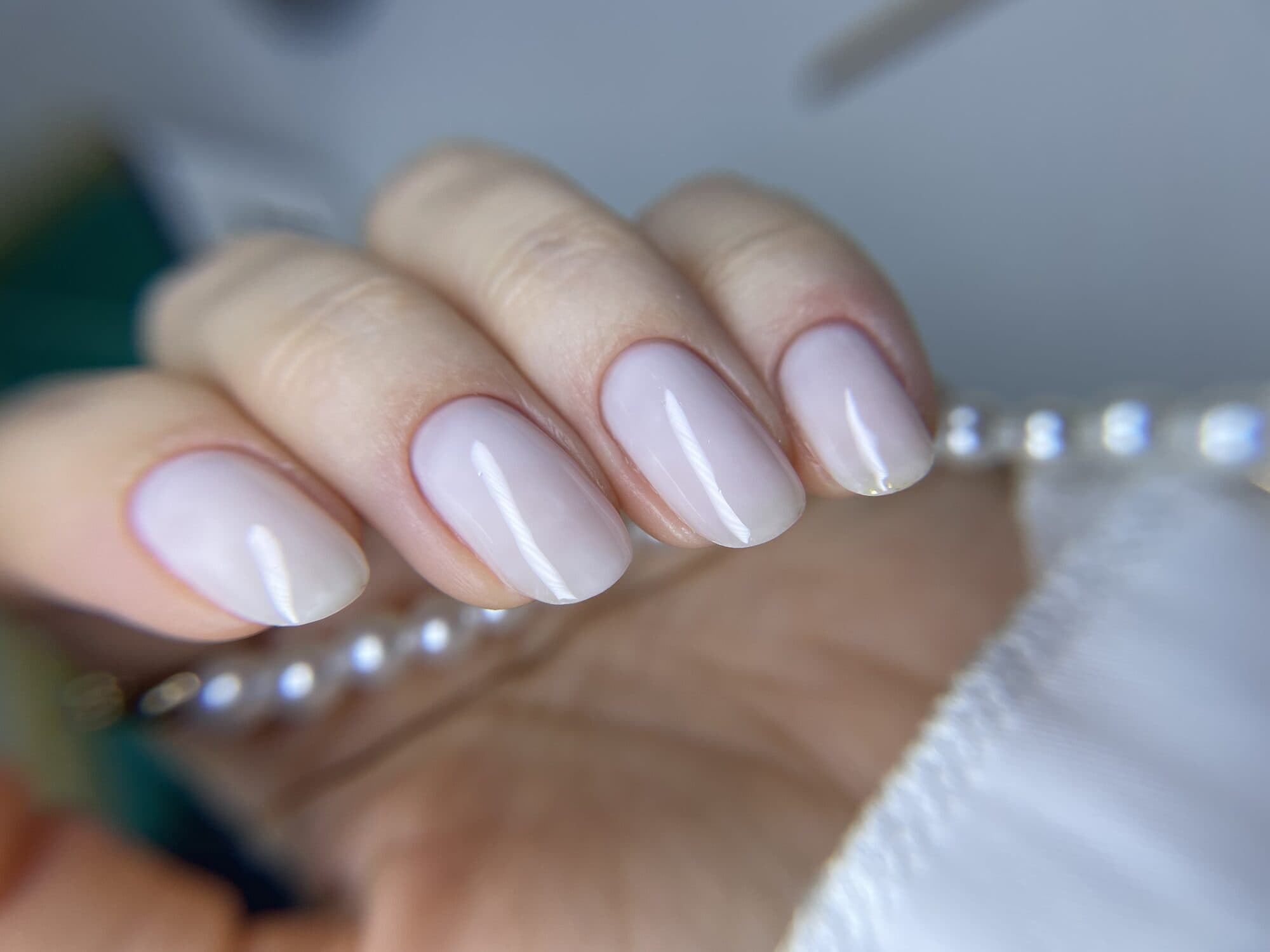 Milky pink square nails with a pearl bracelet